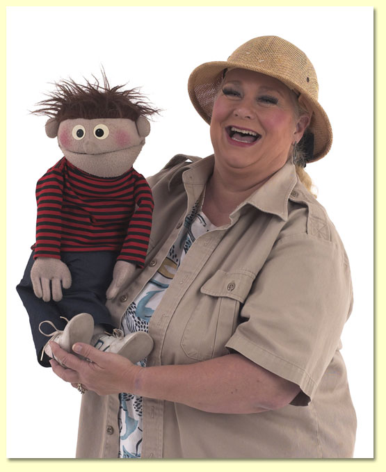 Big picture of Margaret Clauder dressed as Paleo-Maggie for her 2011 show Dig Up A Good Book, shown with Elmer, the puppet.