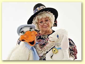 Photo of Mother Goose (played by Margaret Clauder) with Goosey and Lamby perched on her lap.