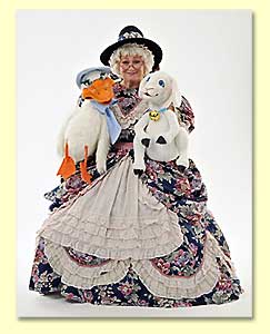 Photograph of Margaret Clauder as Mother Goose, posing with 2 puppets in her lap.